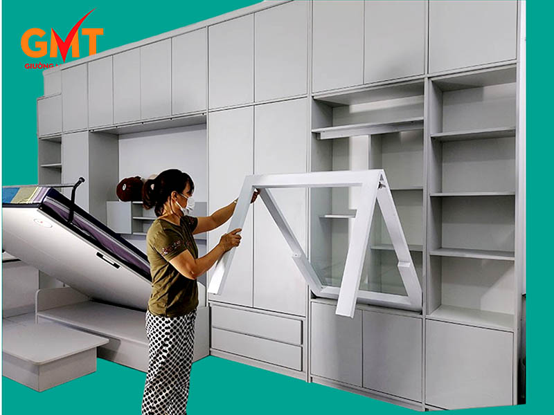 Hãy thử ngay kiểu nội thất này nếu bạn đang sở hữu căn hộ một phòng 2 Hệ nội thất thông minh nguyên khối cho căn hộ một phòng gồm giường gấp kết hợp sofa, tủ quần áo, kệ làm việc, bàn ăn gấp kính trong phòng khách tone trắng xám hiện đại.