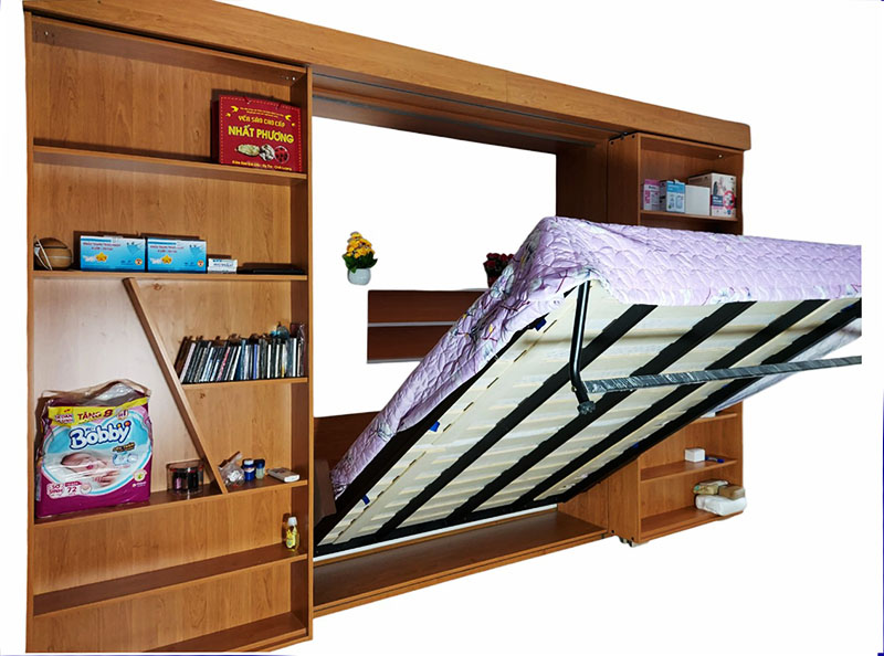 Hình ảnh cho bài viết giá Giường gấp thông minh gỗ màu nâu tích hợp kệ sách và ngăn tủ, đang được mở một phần, cho thấy bên trong có nệm và hệ thống trợ lực